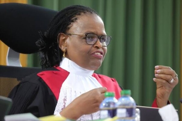 Kenyan Chief Justice Martha Koome with a concerned expression, surrounded by security personnel. The image symbolizes the recent withdrawal of her security detail