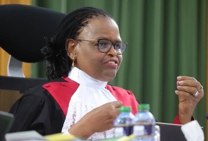Kenyan Chief Justice Martha Koome with a concerned expression, surrounded by security personnel. The image symbolizes the recent withdrawal of her security detail